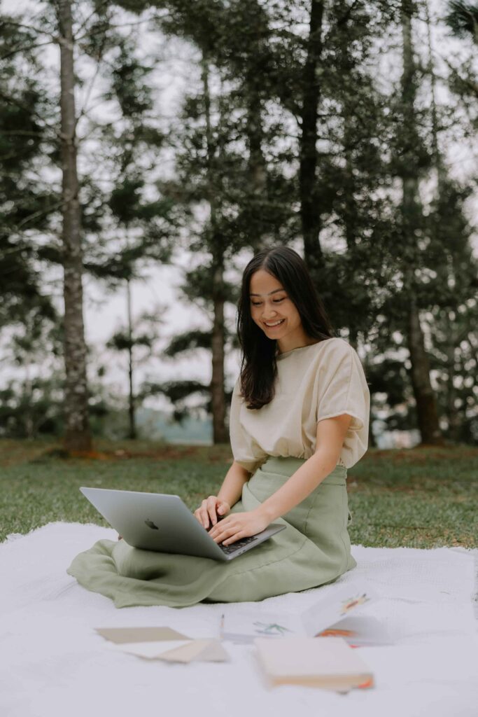 Olumis Studio founder working on a laptop outdoors with branding materials